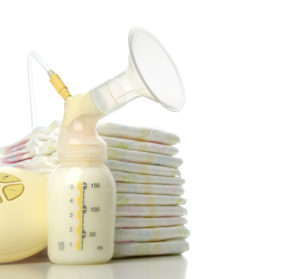 Medical electric breast pump to increase milk supply for breastfeeding mother and stack of diapers isolated on white background. Baby child care concept