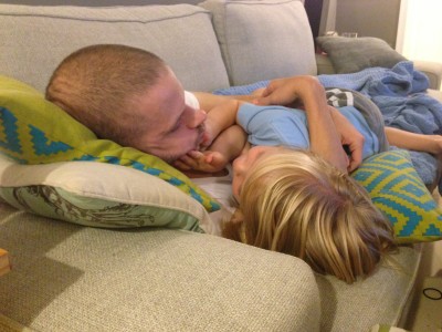 Dad and his young son cuddled up together, napping on the couch