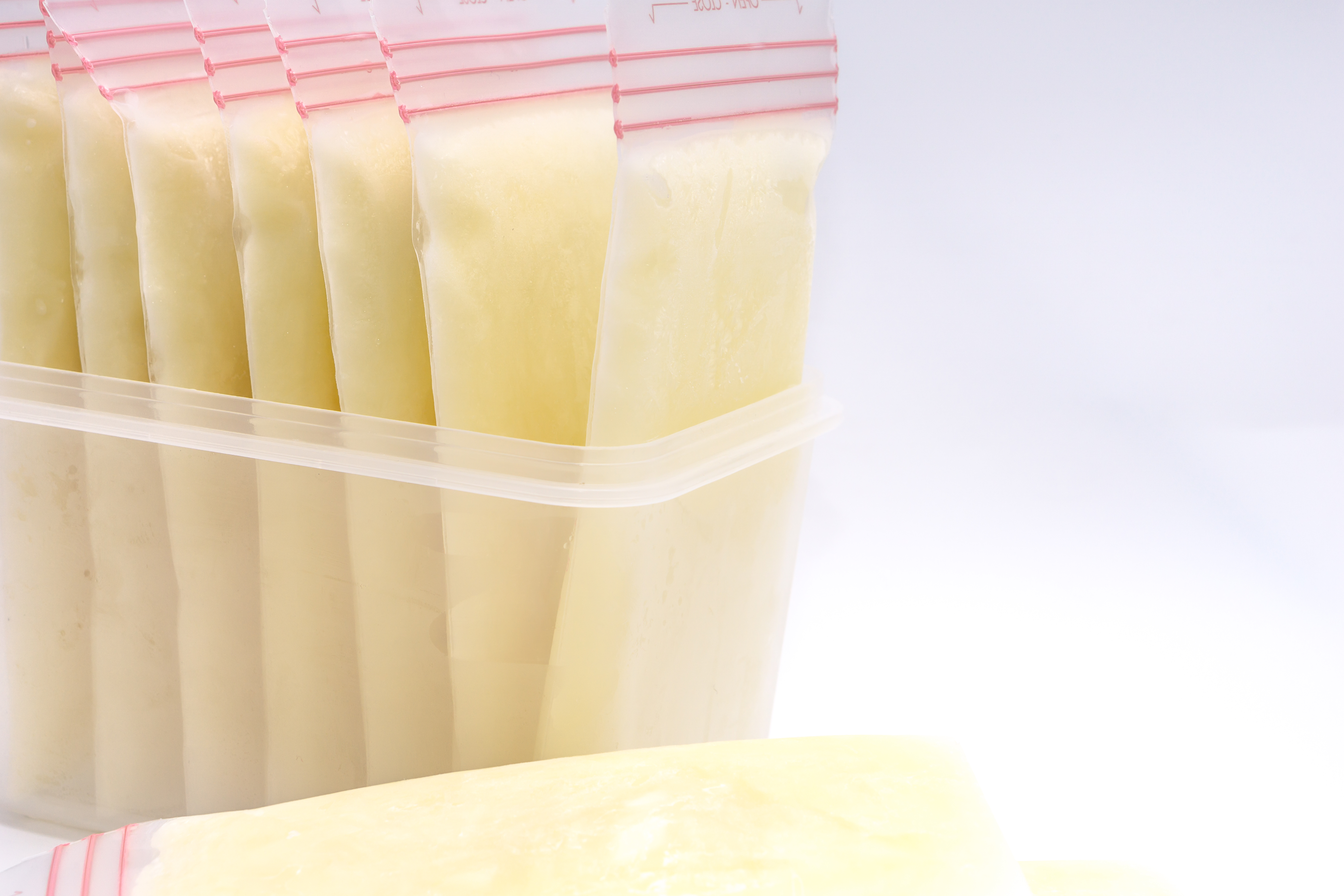 Bags of frozen breast milk stored upright in a plastic container