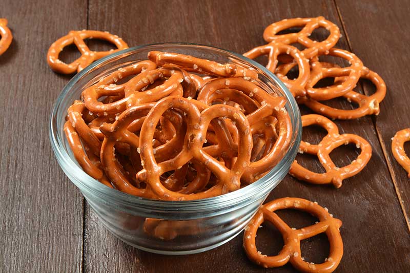 Glass bowl of salted pretzels on a wooden table