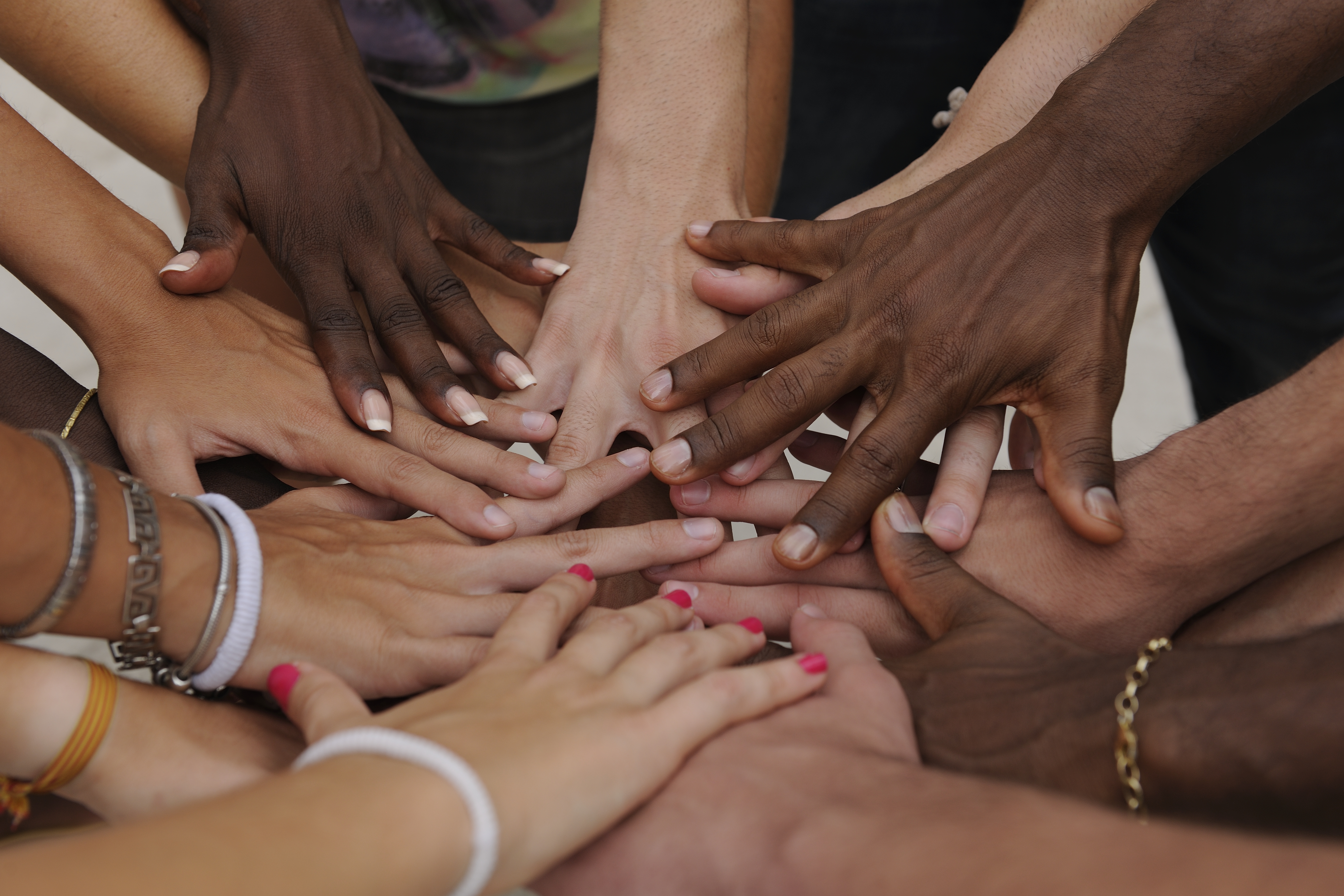 Many hands of different skin tones stacked together in a circle