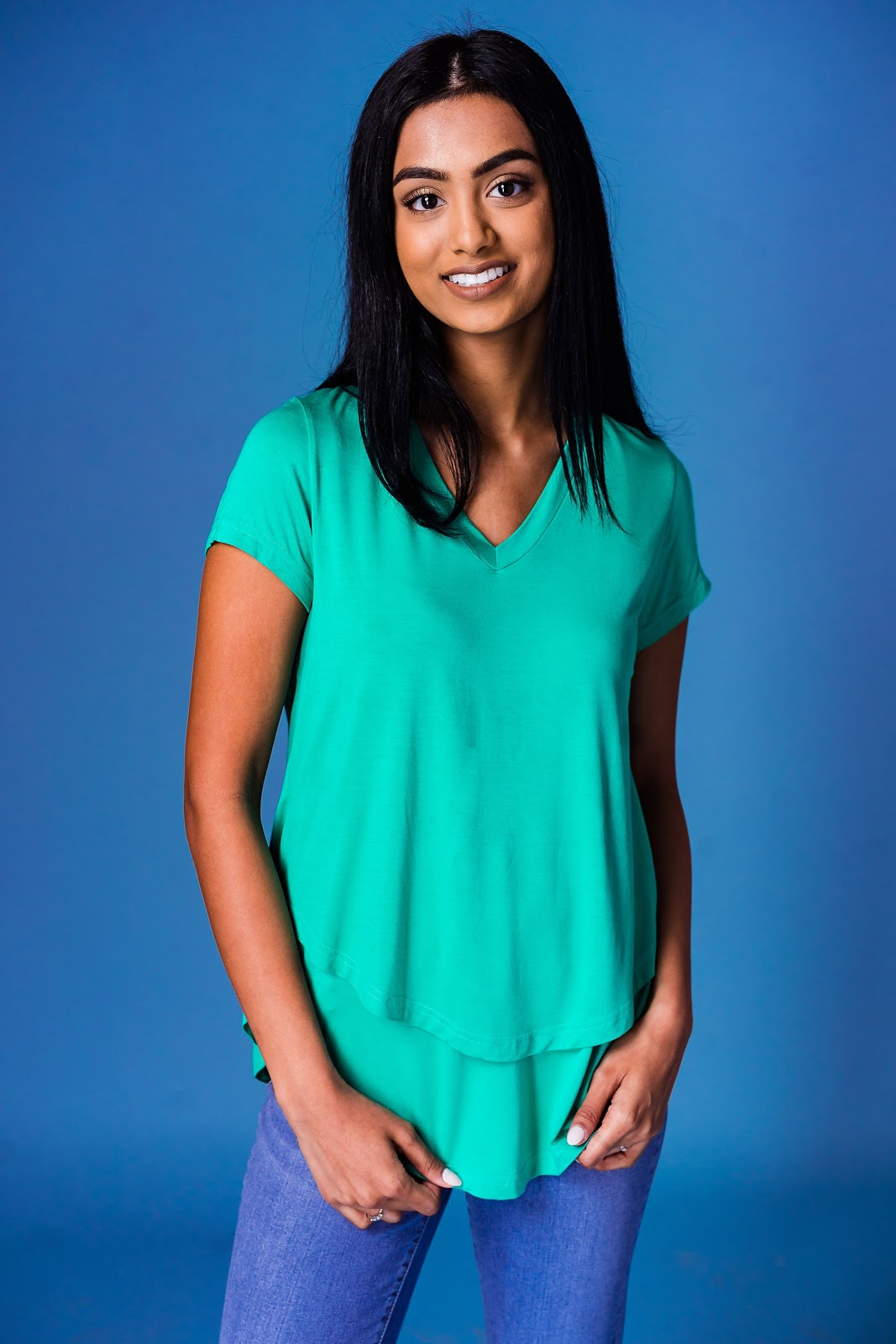Smiling woman in a green layered V-neck nursing top and jeans