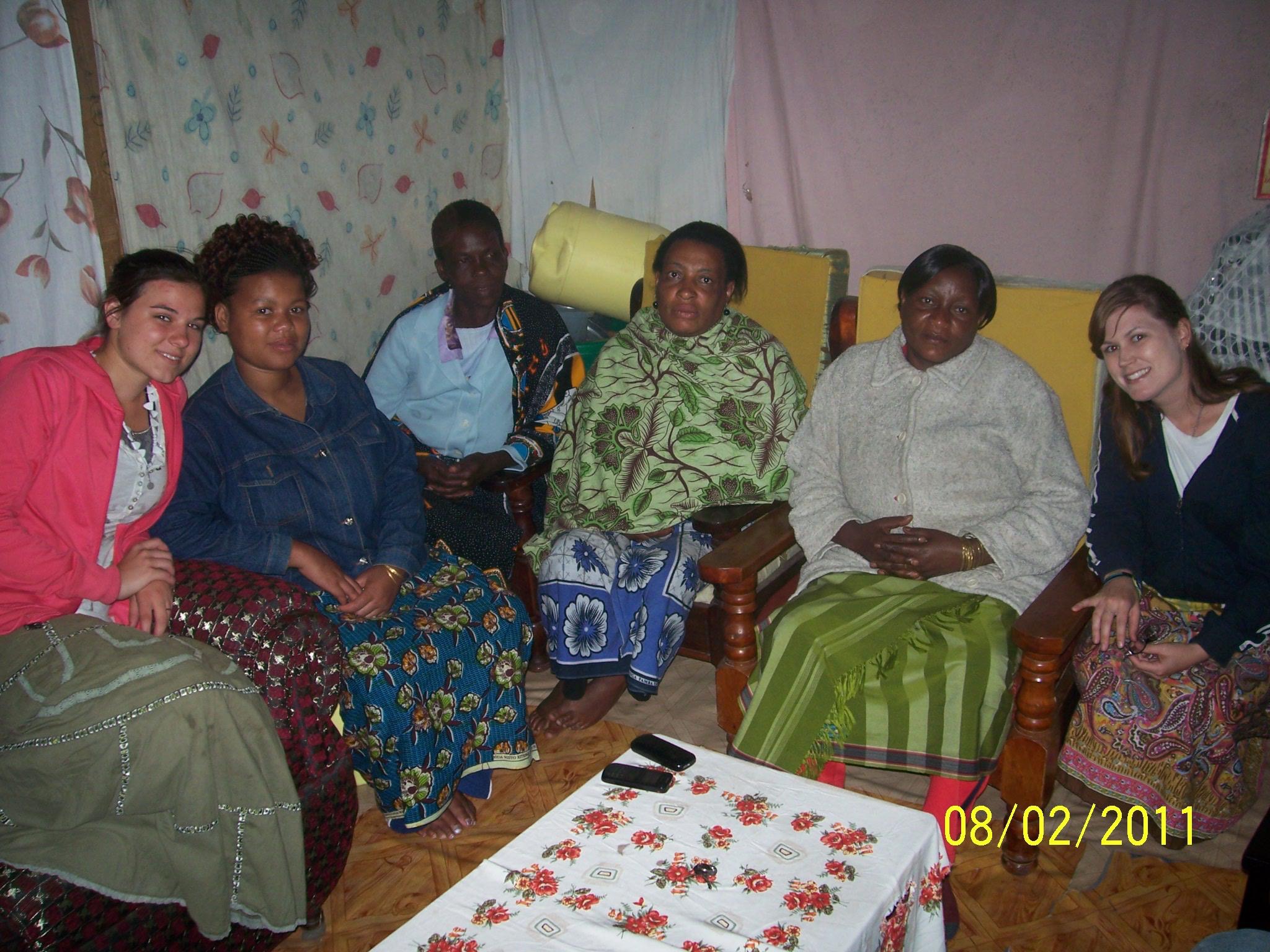 Candace Inge and other women seated together in a small home in Tanzania, photo dated 08/02/2011