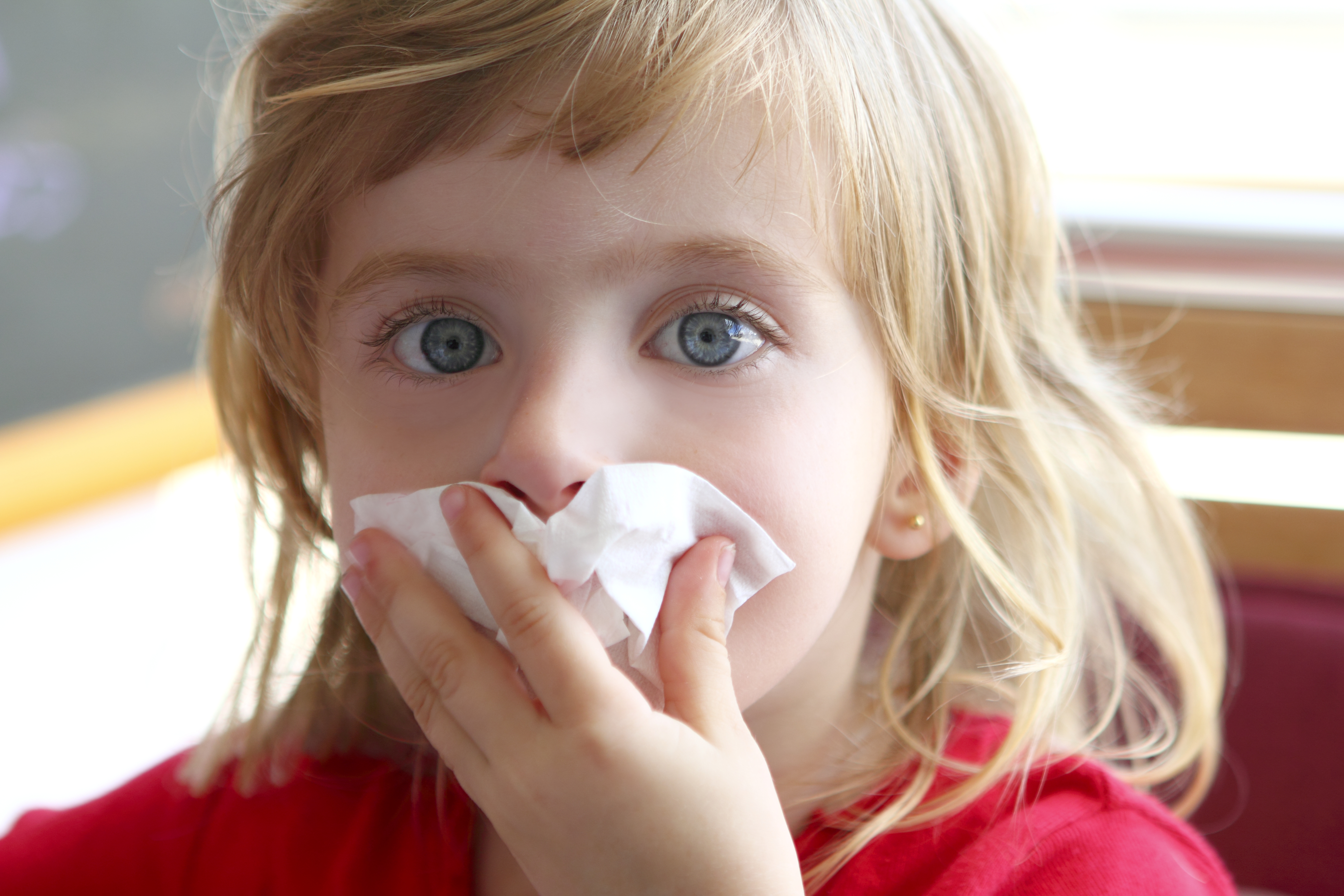Young girl holding a tissue to her nose