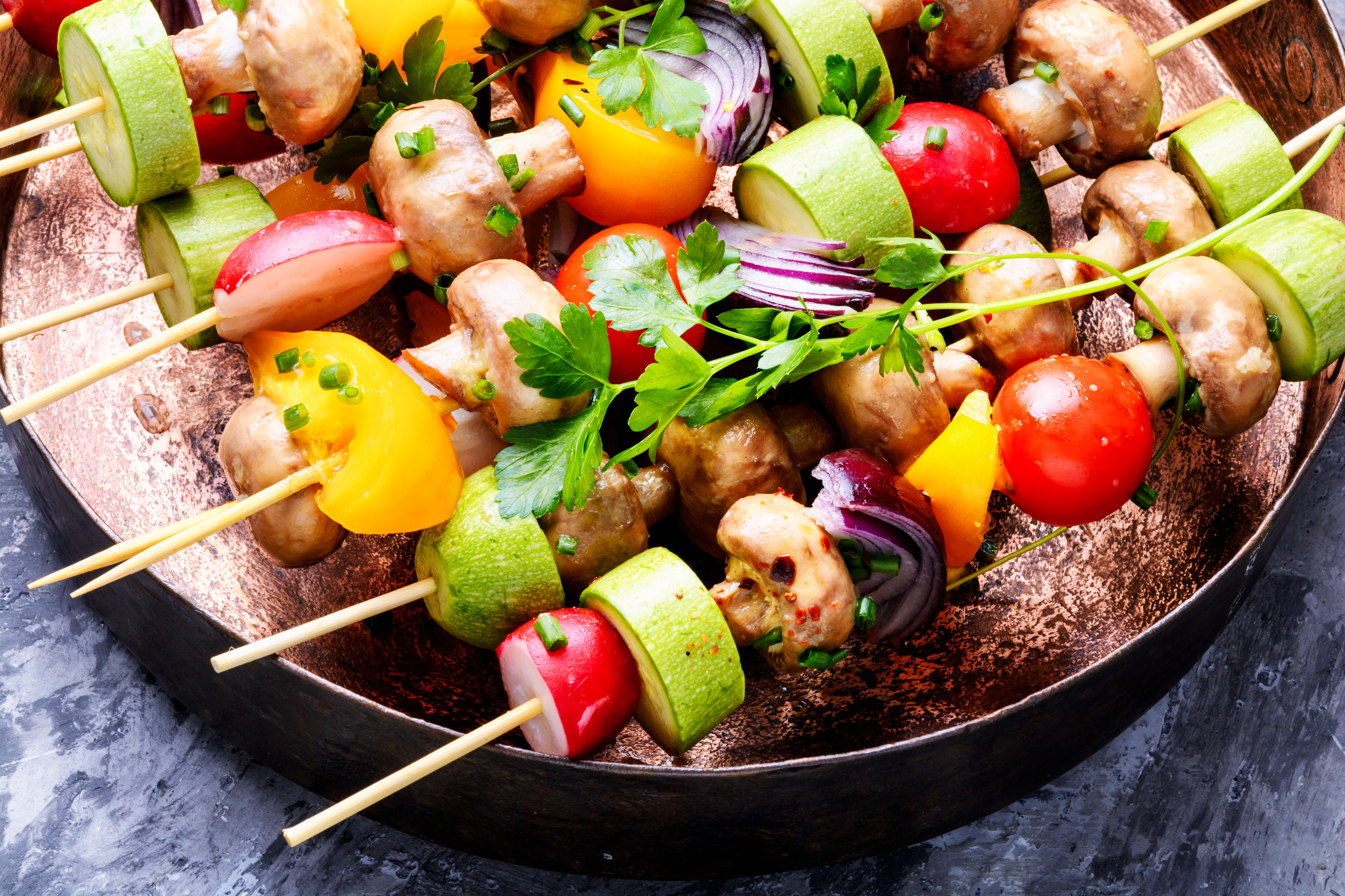 Grilled vegetable skewers of mushrooms, zucchini, peppers and tomatoes in a pan