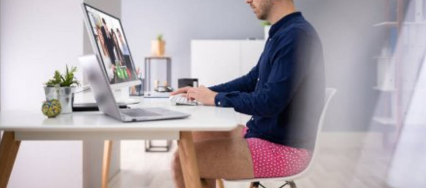 Man on a video call at his desk wearing a dress shirt and pink boxer shorts instead of pants
