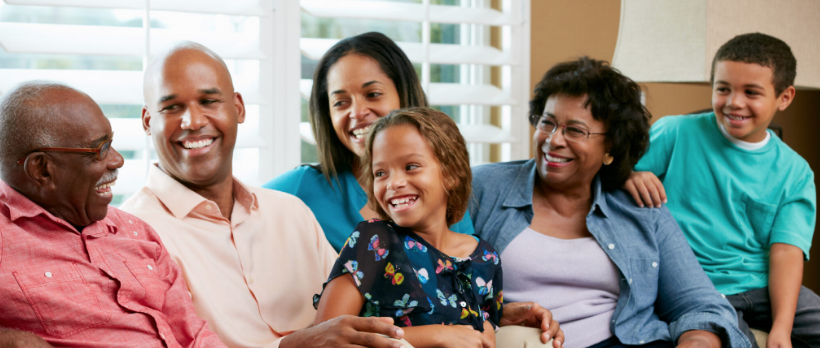 Three generations of a family laughing together on a couch