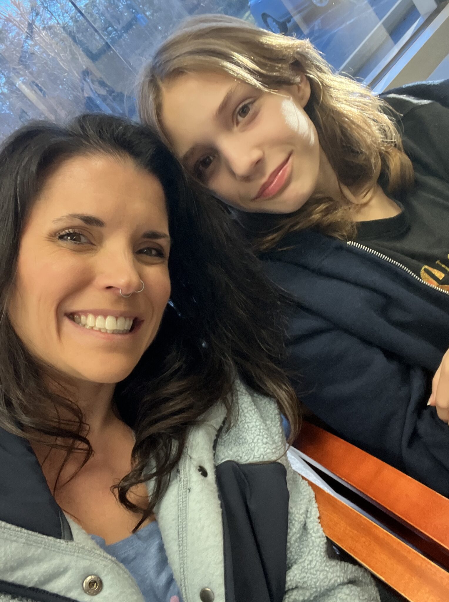 Smiling mom and her daughter taking a selfie together on a bench
