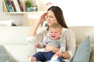 Stressed mom holding a crying baby. Stop saying "You'll miss this someday."